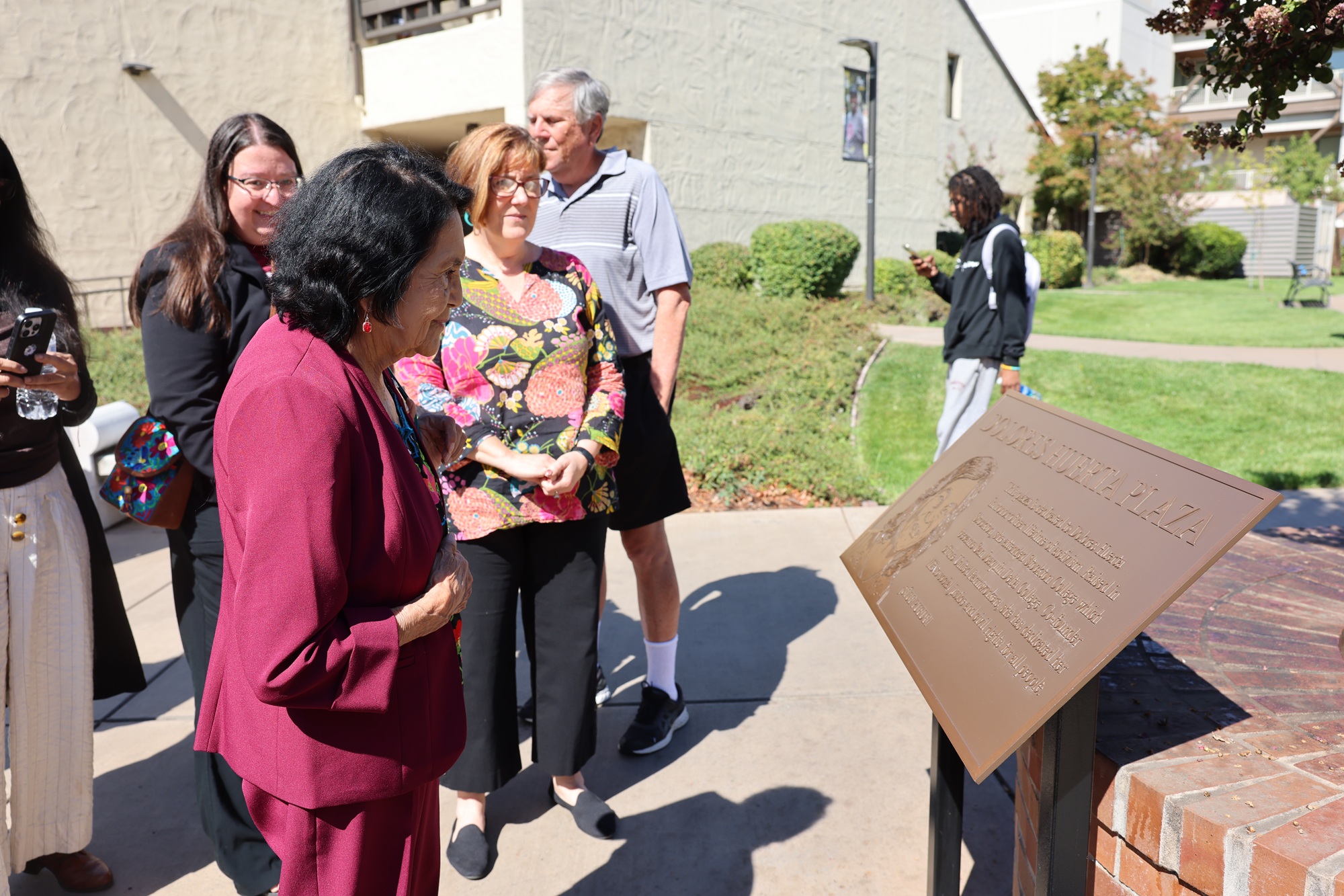 Dolores Huerta reads a plaque in her honor at hte Dolores Huerta Plaza