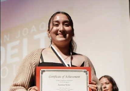 A student holding a graduation certificate from LREA