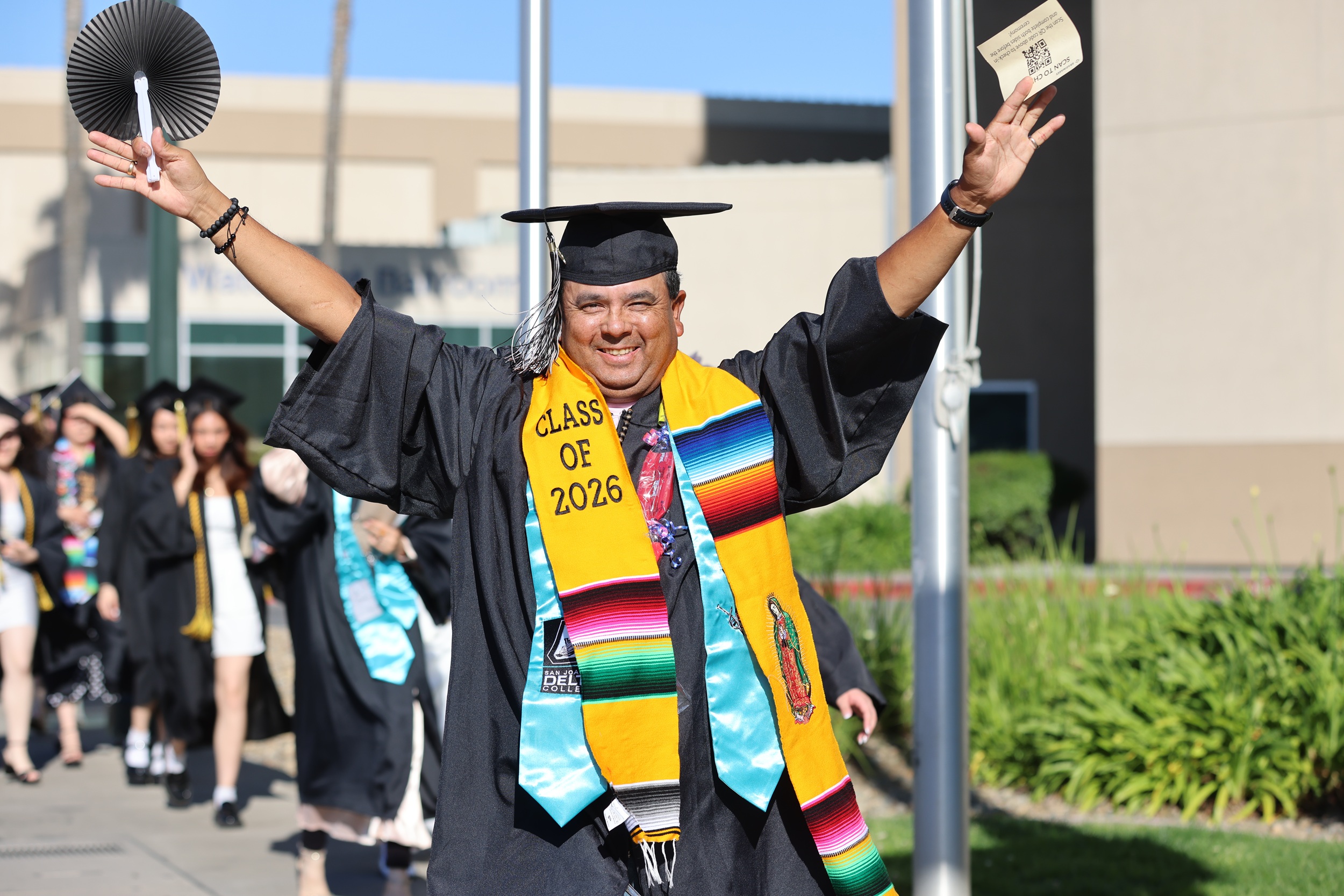 Photo of a graduate walking from the Civic Auditorium to the Arena