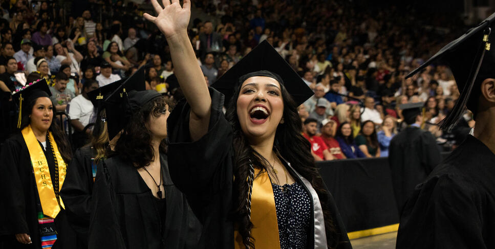 A Delta College graduate waves to her family