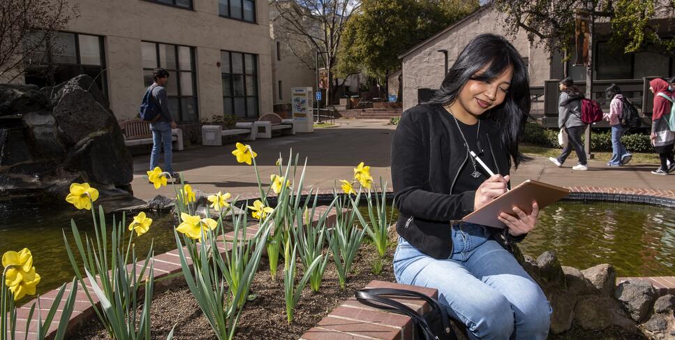 Photo of a student journaling next to the koi pond