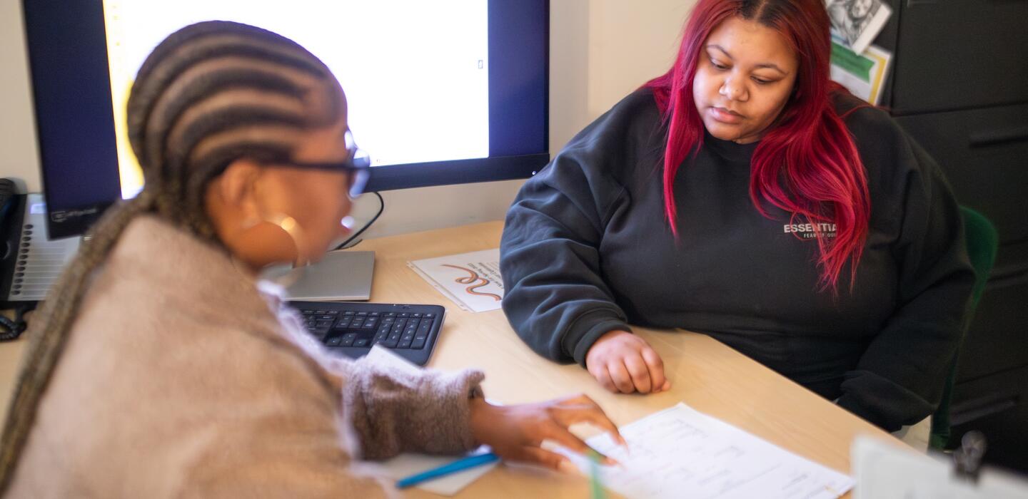 Delta staff member and Delta student sitting across from each other at a work desk looking at a paper