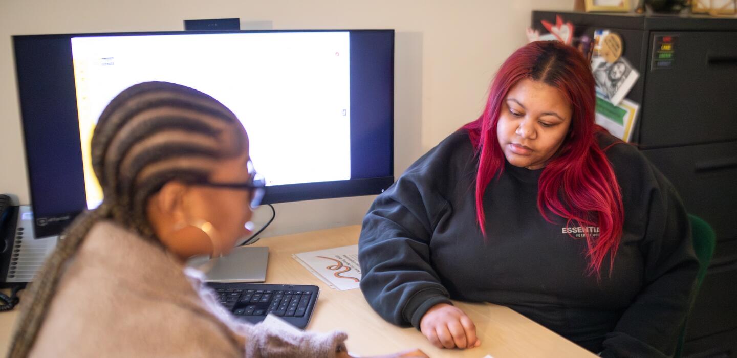 Delta staff member and Delta student sitting across from each other at a work desk looking at a paper