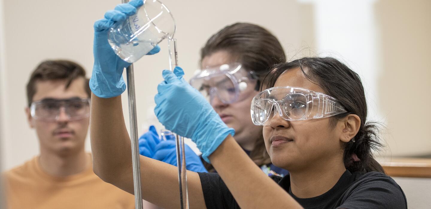 Photo of a chemistry student pouring a liquid