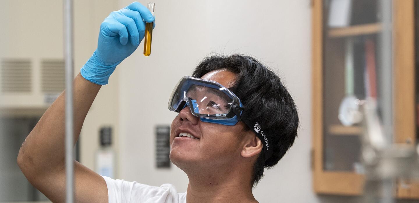A student in chemistry lab looks at a test tube