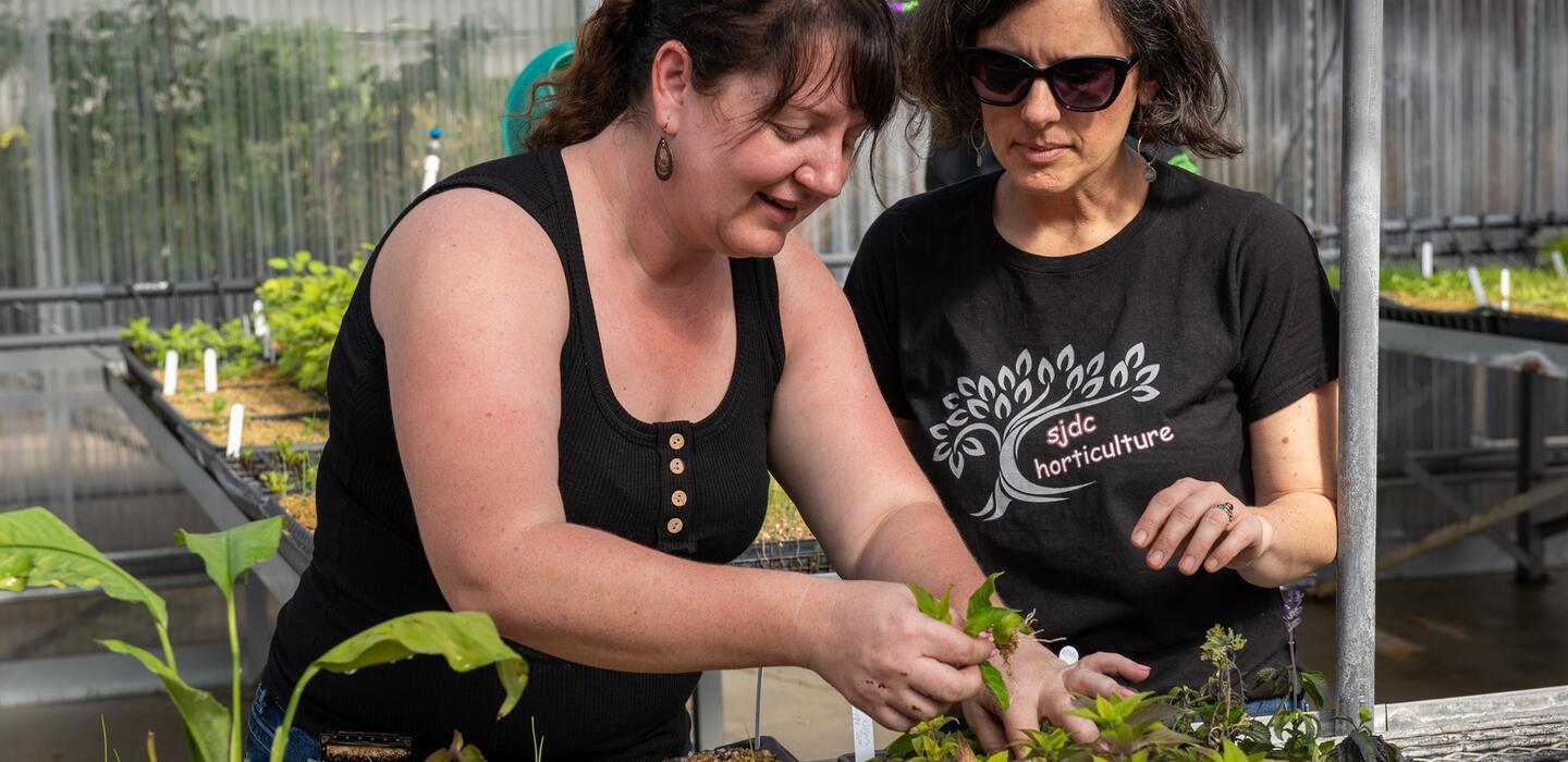 Photo of a faculty member working with a student in Delta's greenhouse