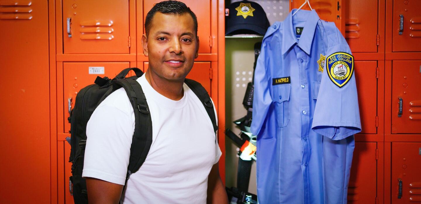 A Delta College police cadet stands with his uniform in the locker room