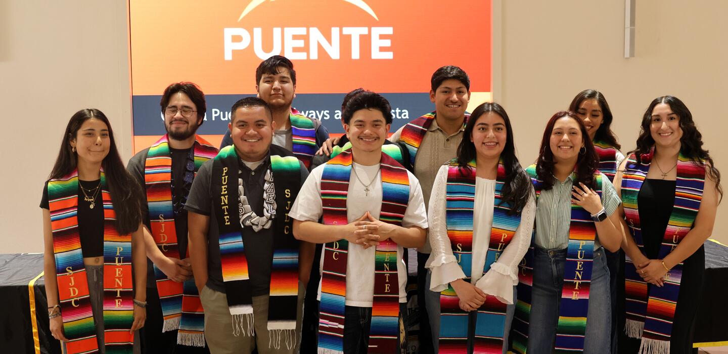 A group of Puente students their Puente stole and smiling for a photo