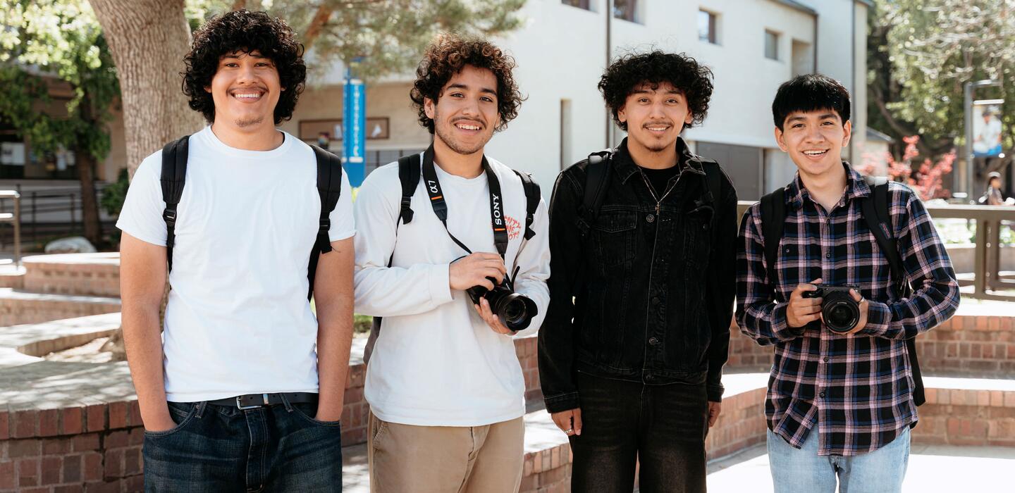 A group of students outside holding cameras and smiling