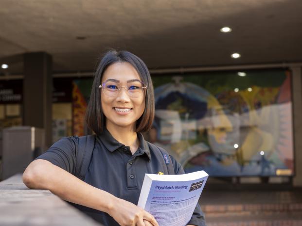 Person holding textbook and smiling