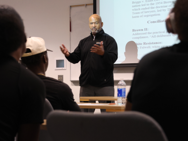 A black speaker is presenting his lecture in the classroom.