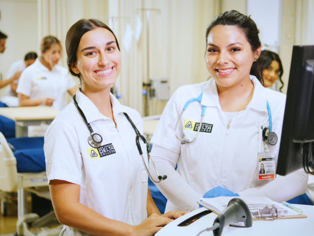 Two female nurses are smiling in a nursing-practice classroom