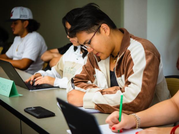 An male Asian student is solving a math-problem