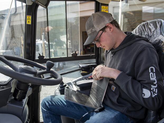 A Caterpillar student checks his laptop before operating heavy machinery