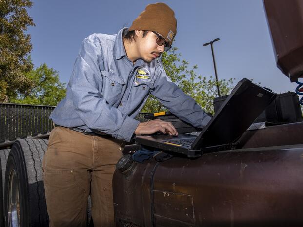 A Caterpillar student works on his laptop.