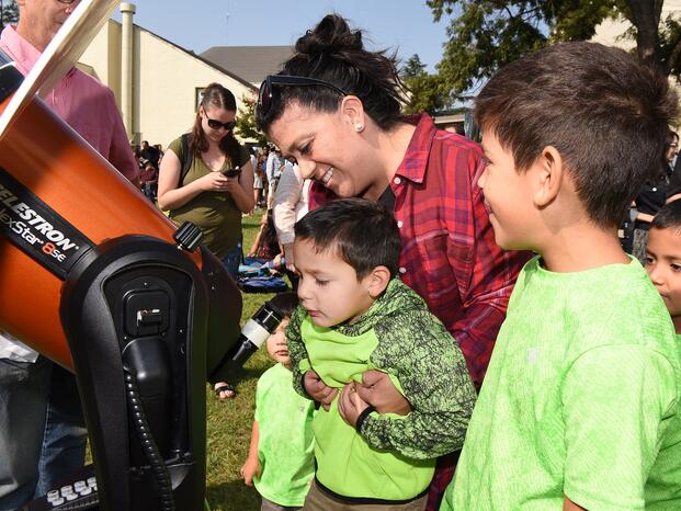 A family peers at a solar eclipse through a telescope 