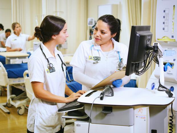 Nursing students discussing information in front of a standing computer