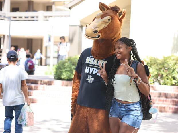 Fierce the Mustang mascot and student smiling together in the Quad