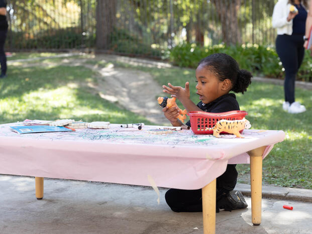 A child plays at a table outside the Child Development Center
