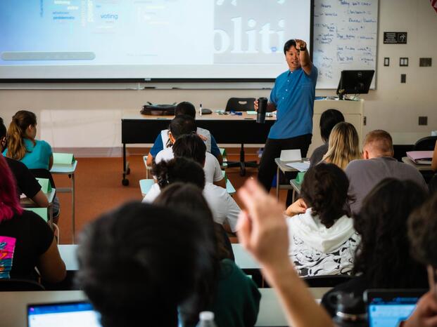 Professor calling on student with hand raised in a classroom