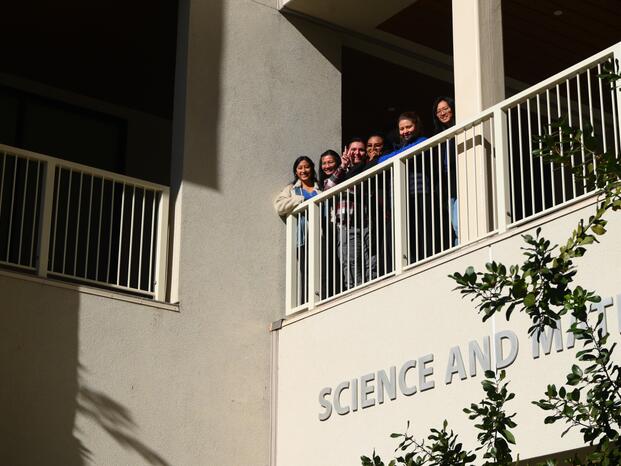 Students standing on second floor of SCMA building smiling 