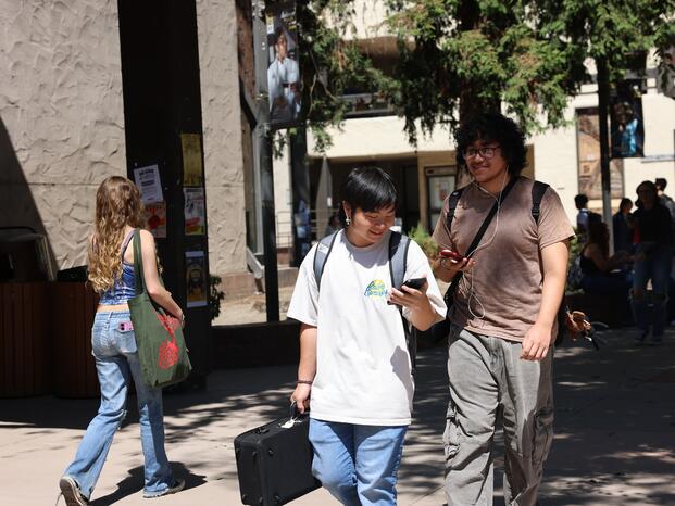 A student checks their phone while walking through campus