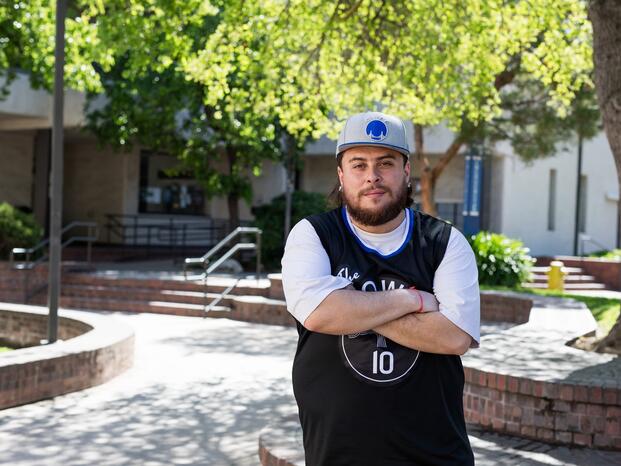 A student crosses his arms and poses for the camera in the Quad