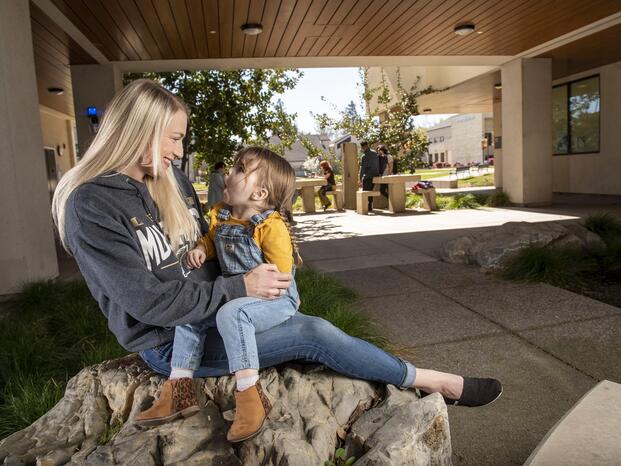 A student parent holds her daughter for a photo