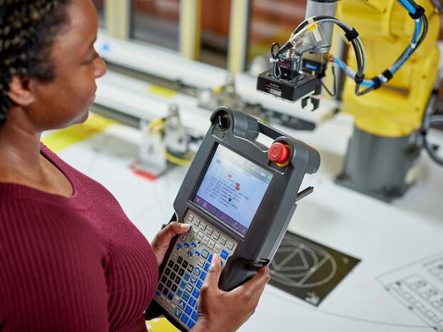 A student holding a remote control for a robotics machine