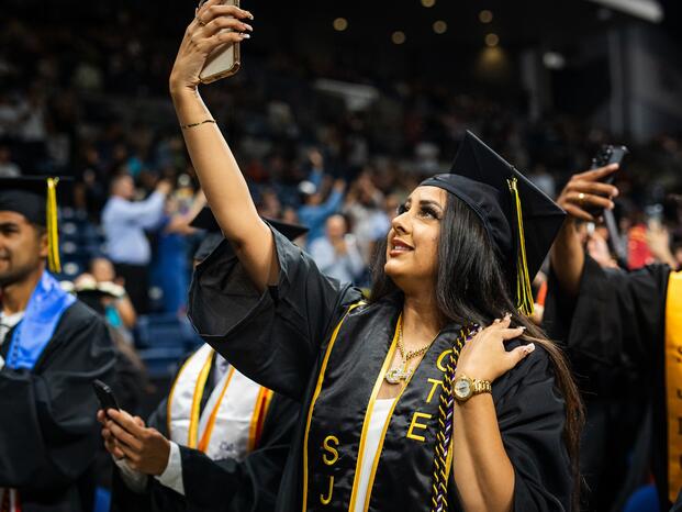 A Delta College graduate snaps a selfie during Commencement