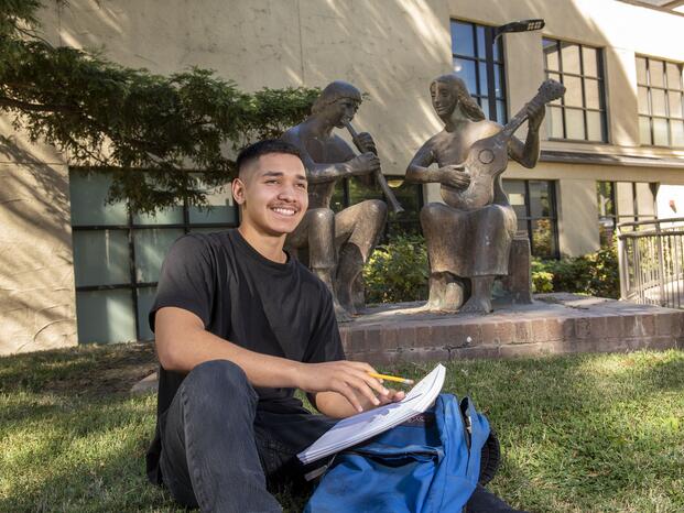 Photo of a Delta student sitting outside Goleman Library