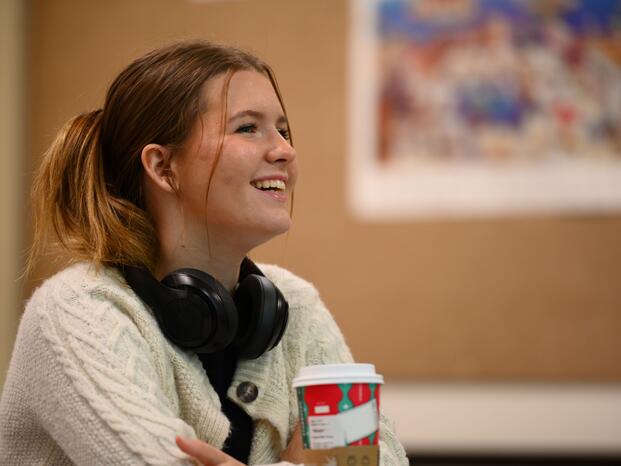 A student sitting down and smiling in a classroom.