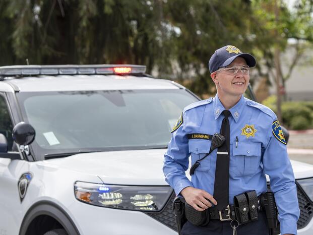 A Delta College police cadet stands next to a vehicle