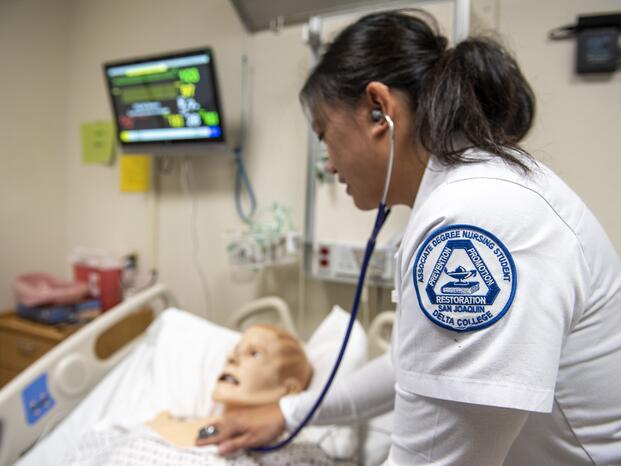 A nursing student listens to a "patient" heartbeat