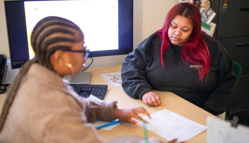 Delta staff member and Delta student sitting across from each other at a work desk looking at a paper