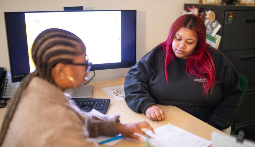 Delta staff member and Delta student sitting across from each other at a work desk looking at a paper