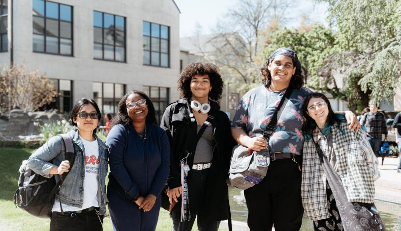 Group of five students standing side by side smiling