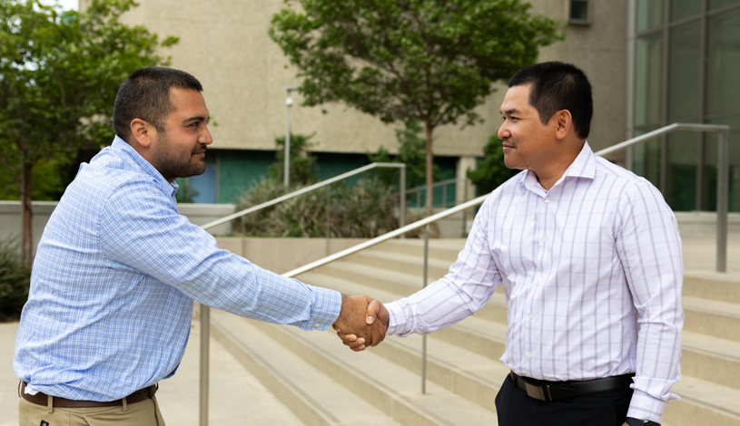 Two men shaking hands in front of a modern building, symbolizing a successful business agreement or partnership.