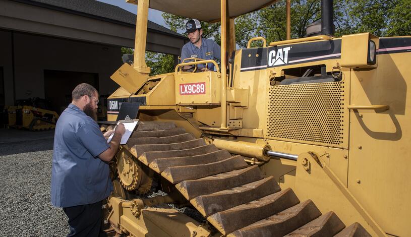 A Caterpillar student checks a piece of heavy equipment