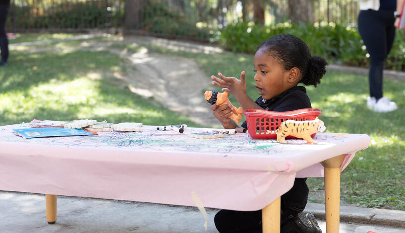 A child plays at a table outside the Child Development Center