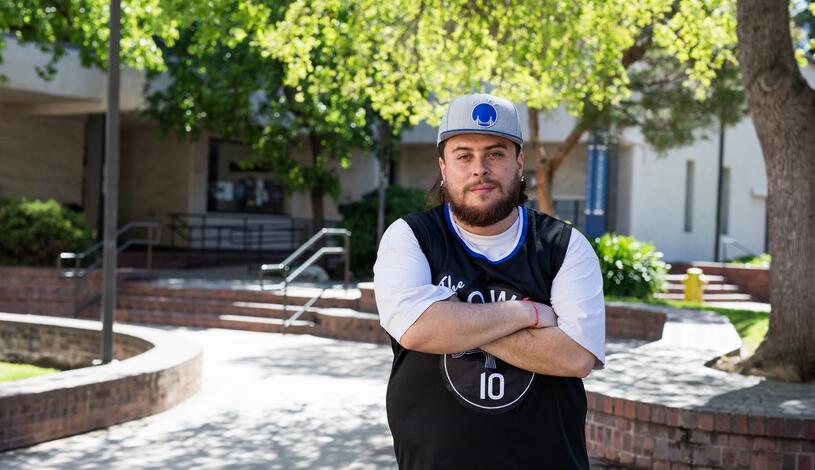 A student crosses his arms and poses for the camera in the Quad