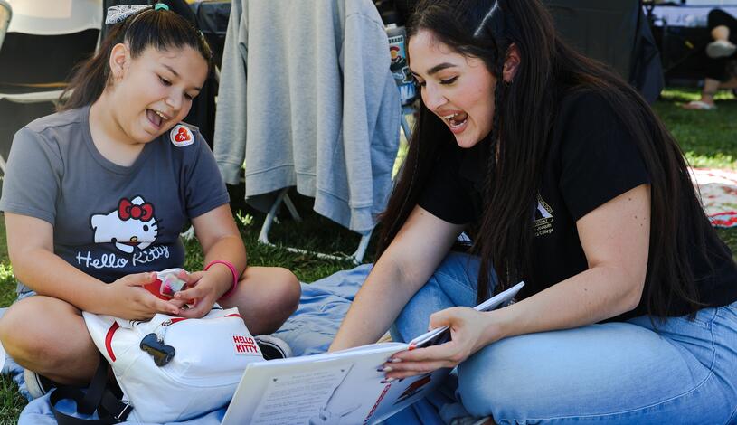 A student volunteer reads to a young child at Family Day at the Park