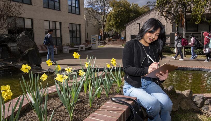 A student student enjoys beautiful weather by the koi pond