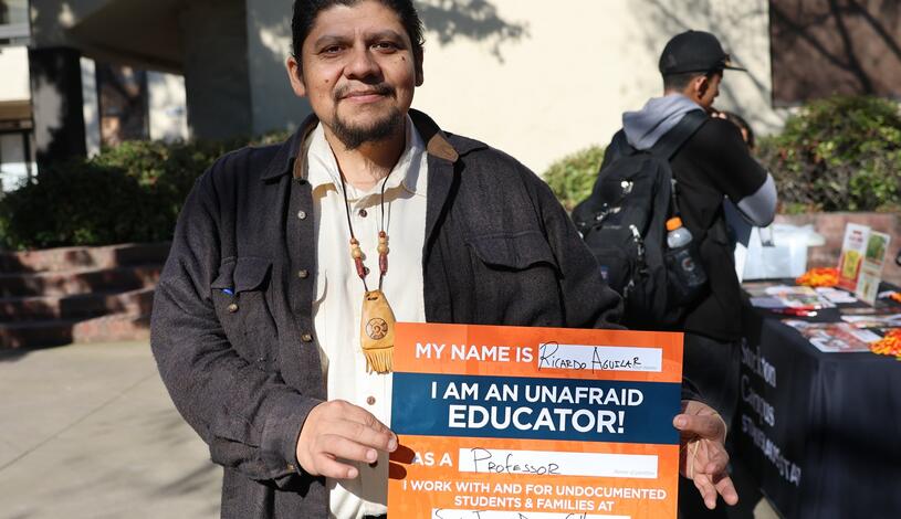 A faculty member holds a sign in support of undocumented students