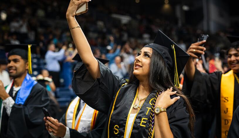 A Delta College graduate snaps a selfie during Commencement