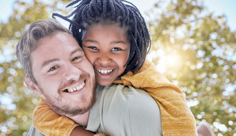 Photo of a resource parent giving a piggyback ride to his daughter.