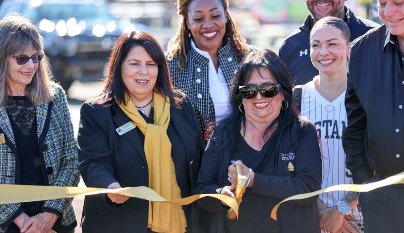 Photo of Board of Trustees President Janet Rivera cutting the ribbon at grand reopening of Delta's Chase Chevrolet Athletics Complex