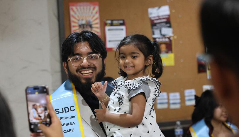 Photo of a graduate holding his daughter