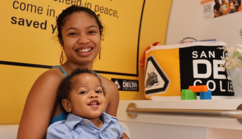 Photo of a student parent sitting in a lactation pod with her son