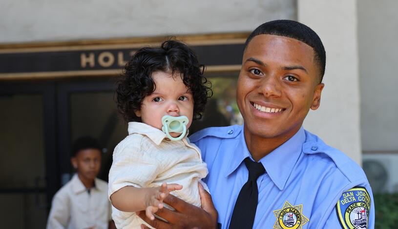 Photo of a graduating police cadet holding a baby